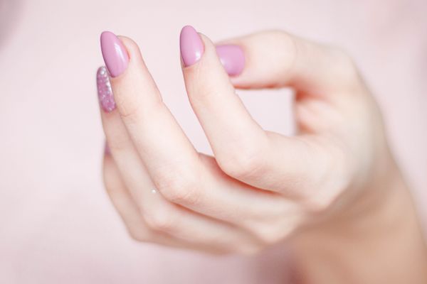 Hand with almond-shaped lilac nails and one glitter accent nail